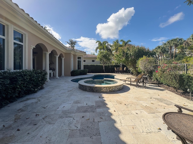 view of patio with a pool with connected hot tub and fence