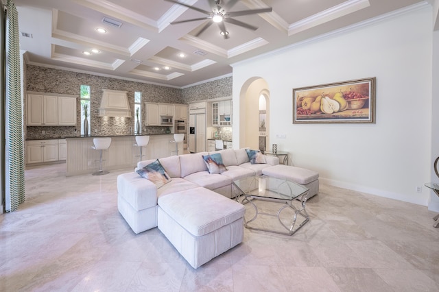 living room with coffered ceiling, crown molding, beam ceiling, ceiling fan, and arched walkways