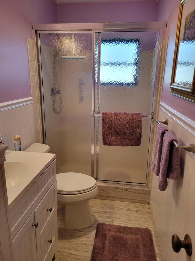 4941 Dovewood Rd Unit A, Boynton Beach, FL 33436 - full bathroom with a wainscoted wall, wood finished floors, toilet, vanity, and a stall shower