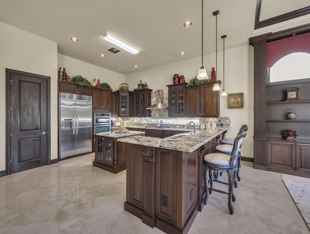 17384 Vistancia Cir, Boca Raton, FL 33496 - kitchen with tasteful backsplash, a breakfast bar, appliances with stainless steel finishes, dark brown cabinetry, and a peninsula