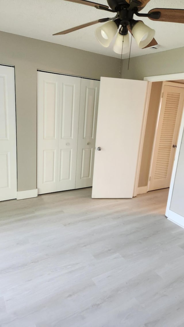 unfurnished bedroom featuring light wood-type flooring, ceiling fan, and baseboards