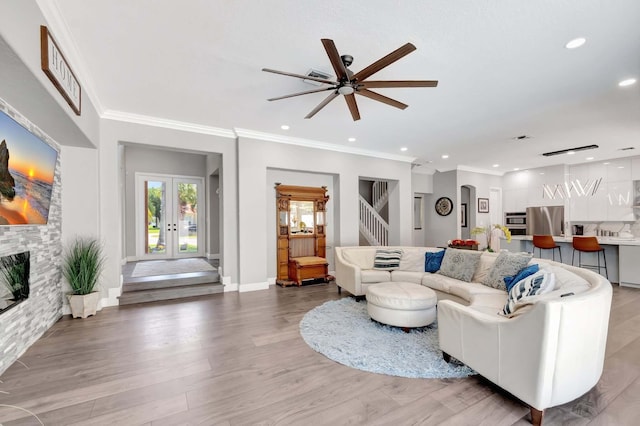 living area featuring ceiling fan, crown molding, recessed lighting, light wood-type flooring, and stairs