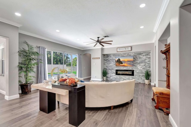 living area with a glass covered fireplace, wood finished floors, baseboards, ceiling fan, and recessed lighting