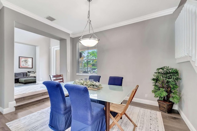 dining area featuring crown molding, baseboards, and wood finished floors