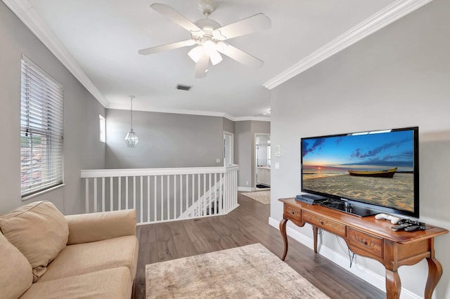 living room featuring wood finished floors, ornamental molding, a ceiling fan, and baseboards