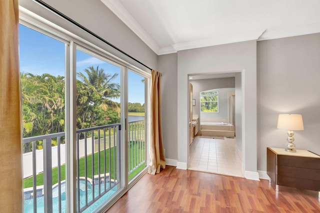 corridor featuring crown molding, baseboards, and light wood finished floors