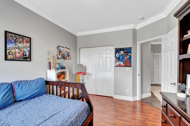 bedroom featuring dark wood finished floors, ornamental molding, a closet, and baseboards