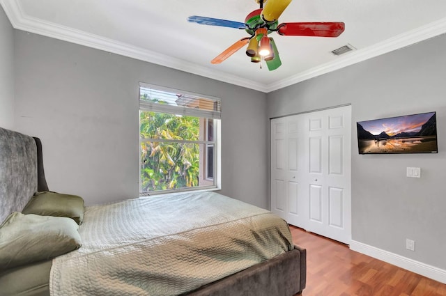 bedroom with crown molding, wood finished floors, a closet, ceiling fan, and baseboards