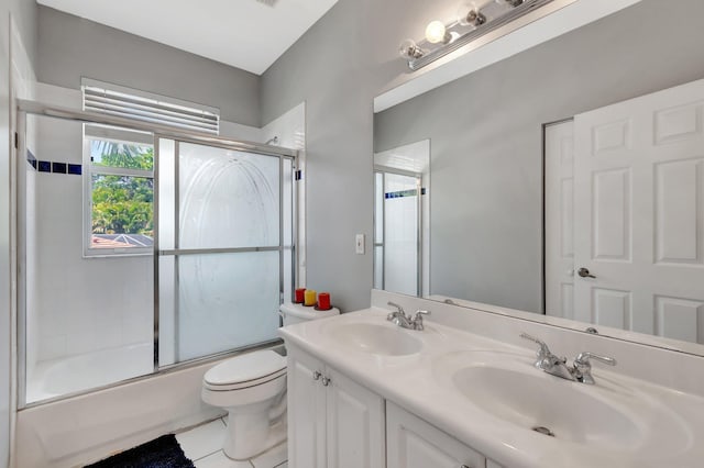 full bath with toilet, shower / bath combination with glass door, double vanity, and tile patterned floors