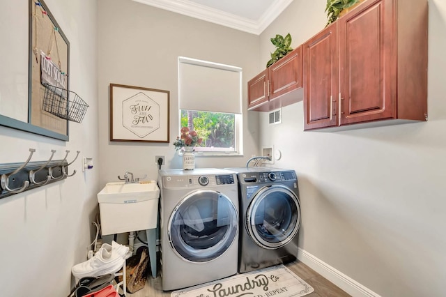 laundry room with cabinet space, crown molding, washing machine and clothes dryer, and baseboards