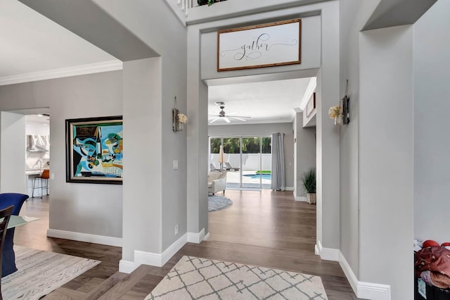 foyer entrance with baseboards, wood finished floors, ornamental molding, and a ceiling fan