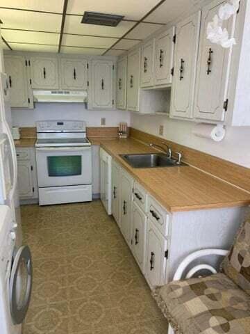 1905 NW 18th St Unit 101, Delray Beach, FL 33445 - kitchen with white appliances, a sink, under cabinet range hood, washer / clothes dryer, and light countertops