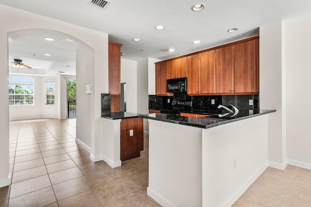 kitchen featuring light tile patterned floors, visible vents, ceiling fan, black appliances, and decorative backsplash