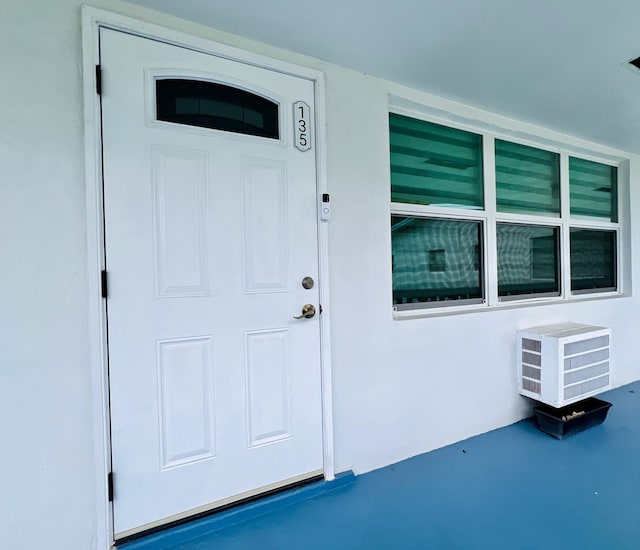 135 Dorchester F, West Palm Beach, FL 33417 - property entrance with a wall unit AC and stucco siding