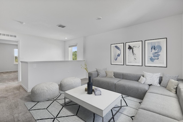 living room featuring visible vents, baseboards, light carpet, and a healthy amount of sunlight