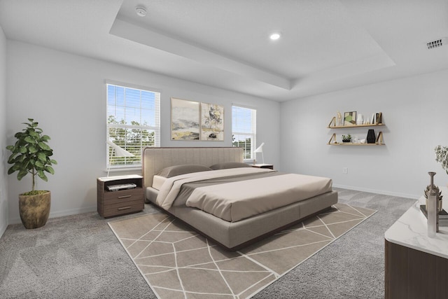bedroom featuring light carpet, visible vents, a tray ceiling, and baseboards