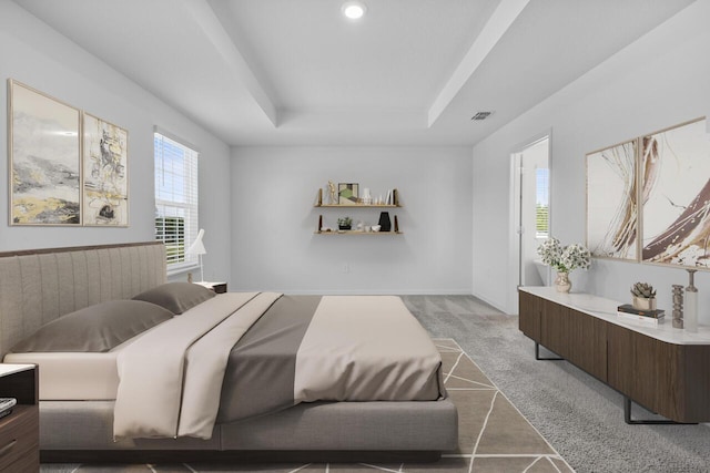bedroom with a tray ceiling, multiple windows, visible vents, and light carpet