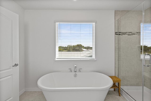 bathroom with a freestanding bath, baseboards, a shower stall, and tile patterned flooring