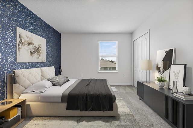 bedroom featuring carpet, a textured ceiling, an accent wall, wallpapered walls, and baseboards