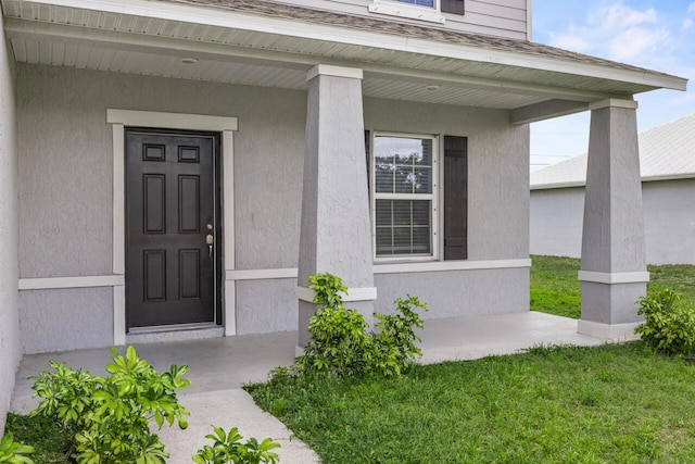 property entrance featuring roof with shingles, stucco siding, and covered porch