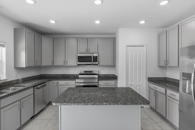 kitchen featuring gray cabinets, a center island, appliances with stainless steel finishes, and light tile patterned floors