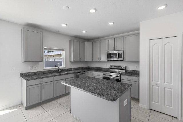 kitchen with gray cabinets, recessed lighting, a kitchen island, stainless steel appliances, and a sink