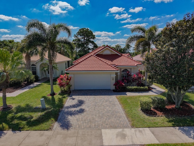 mediterranean / spanish home with a tiled roof, stucco siding, an attached garage, decorative driveway, and a front yard