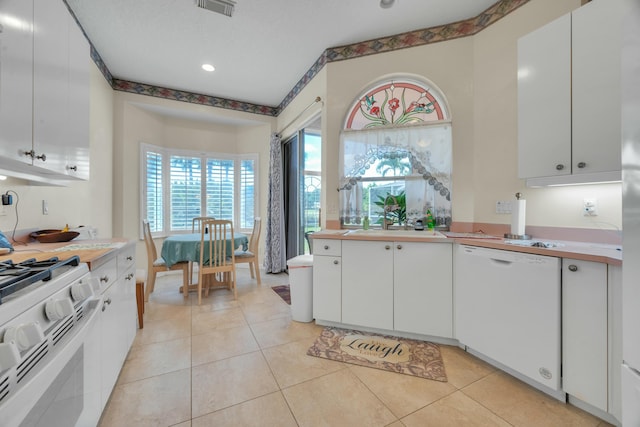 kitchen featuring white cabinets, visible vents, a ceiling fan, light tile patterned floors, and white appliances