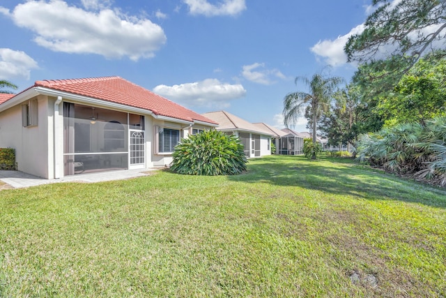 rear view of property with stucco siding, a yard, and a tiled roof