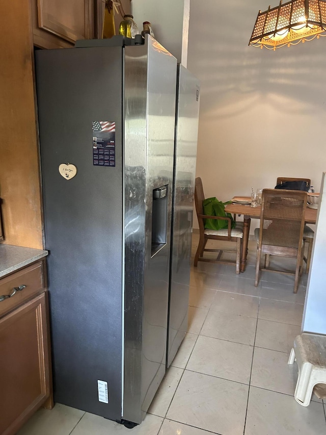 kitchen featuring brown cabinets, light tile patterned flooring, and stainless steel fridge