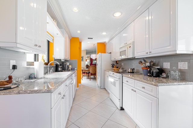 kitchen with light tile patterned floors, white appliances, white cabinets, a sink, and decorative backsplash