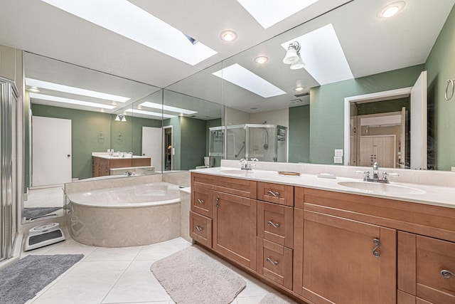 full bathroom featuring a shower stall, a skylight, a garden tub, and a sink