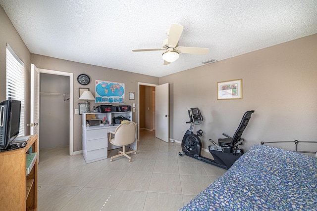 bedroom with light tile patterned floors, a ceiling fan, and a textured ceiling