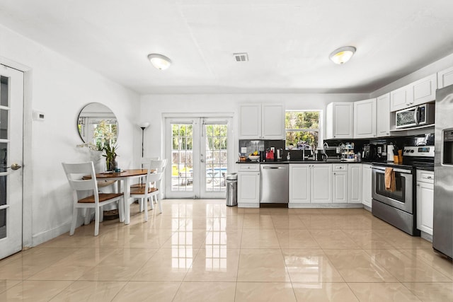 941 NW 26th Ct, Wilton Manors, FL 33311 - kitchen with tasteful backsplash, visible vents, white cabinets, appliances with stainless steel finishes, and dark countertops