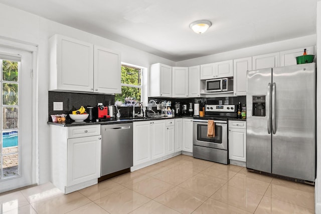 941 NW 26th Ct, Wilton Manors, FL 33311 - kitchen with white cabinets, appliances with stainless steel finishes, a sink, dark countertops, and decorative backsplash