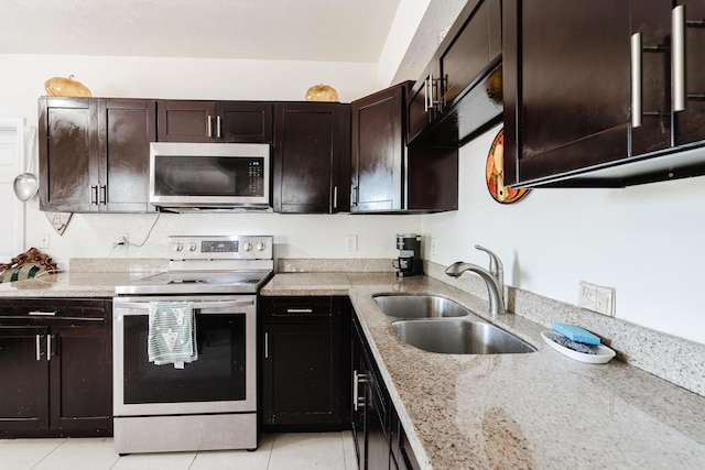 1285 NE 154th St, North Miami Beach, FL 33162 - kitchen with appliances with stainless steel finishes, a sink, light tile patterned floors, light stone countertops, and dark brown cabinetry