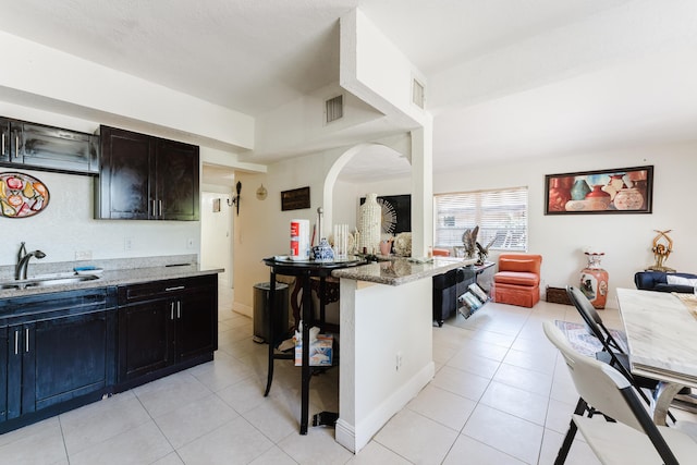 1285 NE 154th St, North Miami Beach, FL 33162 - kitchen featuring a sink, light tile patterned floors, light stone countertops, open floor plan, and a kitchen bar