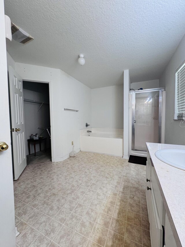 5155 NW N Macedo Blvd, Port Saint Lucie, FL 34983 - full bath featuring a textured ceiling, a shower stall, a bath, vanity, and a walk in closet