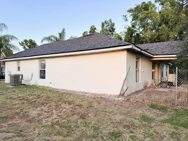 5155 NW N Macedo Blvd, Port Saint Lucie, FL 34983 - view of side of property with central air condition unit, stucco siding, and roof with shingles