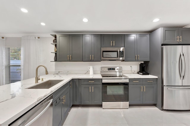 kitchen with open shelves, a sink, light stone countertops, gray cabinets, and stainless steel appliances