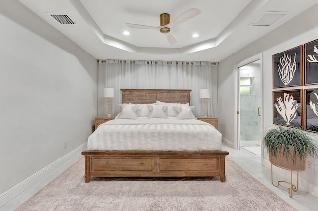 bedroom with a raised ceiling, recessed lighting, visible vents, and connected bathroom