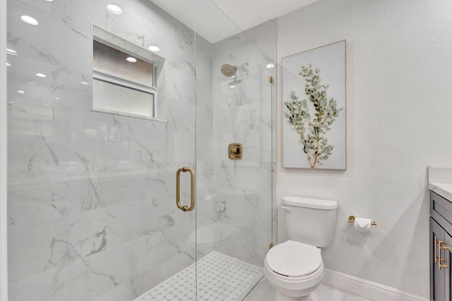 bathroom with a marble finish shower, toilet, vanity, and baseboards