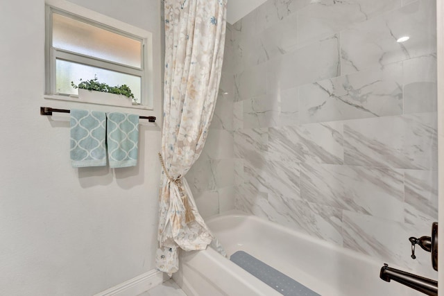 bathroom with shower / bath combo and baseboards