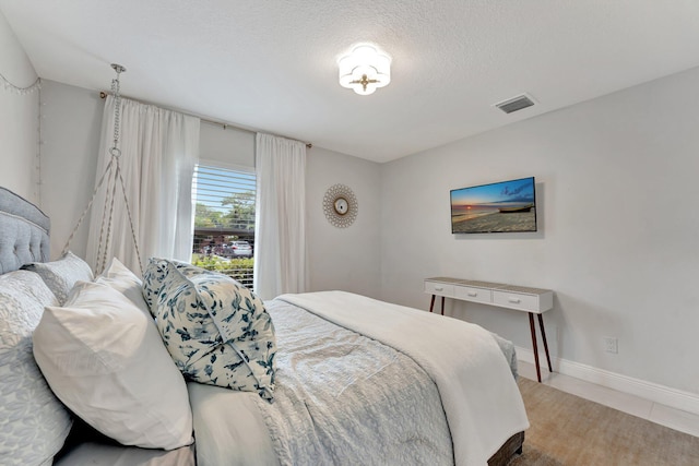 tiled bedroom with a textured ceiling, baseboards, and visible vents