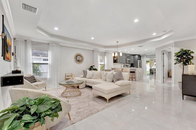 living room with a raised ceiling, a healthy amount of sunlight, and visible vents
