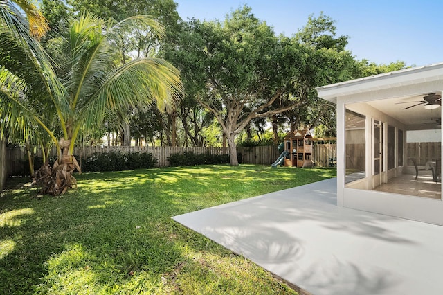 view of yard with a sunroom, a fenced backyard, a ceiling fan, a patio area, and a playground