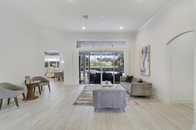 living room with visible vents, baseboards, arched walkways, crown molding, and light wood-style flooring