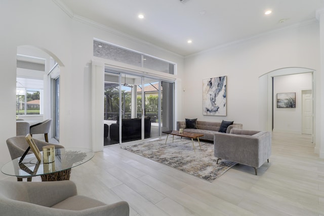 living area with arched walkways, a high ceiling, ornamental molding, and recessed lighting