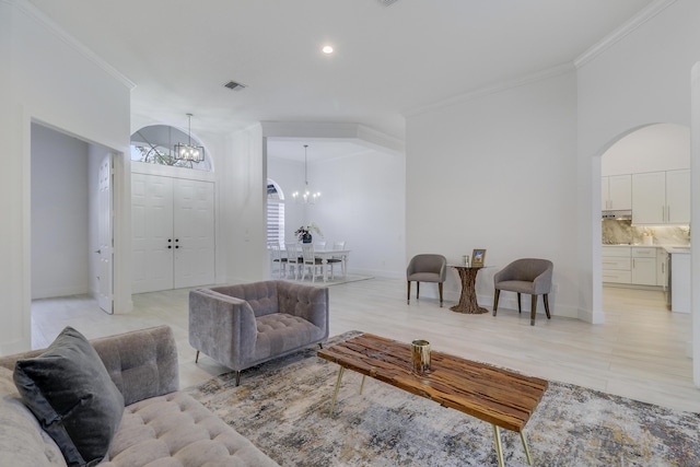 living area with a chandelier, arched walkways, baseboards, and ornamental molding