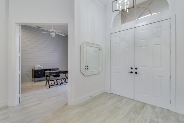 foyer featuring crown molding, wood finished floors, ceiling fan with notable chandelier, and baseboards